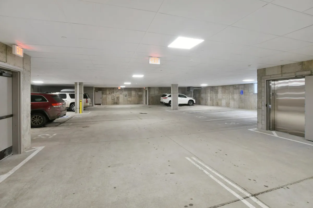 A heated underground parking garage showing clearly marked parking spaces, modern lighting, and vehicles parked in a clean, accessible environment. The image evokes safety, warmth, and ease of access regardless of weather conditions.