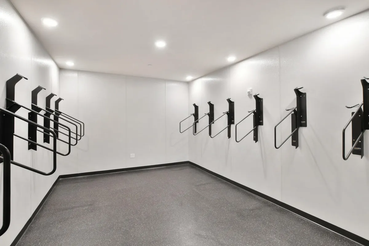 A well-organized interior bike and gear storage room featuring wall-mounted bike racks and smooth, easy-to-clean surfaces. The area feels secure and functional, emphasizing convenience for active residents who need a space for outdoor gear.
