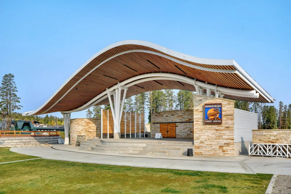 A lively outdoor stage with a curved roof structure and stone facade, surrounded by open space for crowds. The area is set for concerts, performances, and community events, capturing the spirit of Hideaway Park and its year-round festivities.
